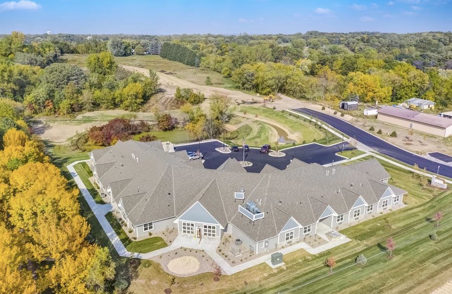 Aerial view of a large building surrounded by landscaped grounds and a parking lot in a rural area.