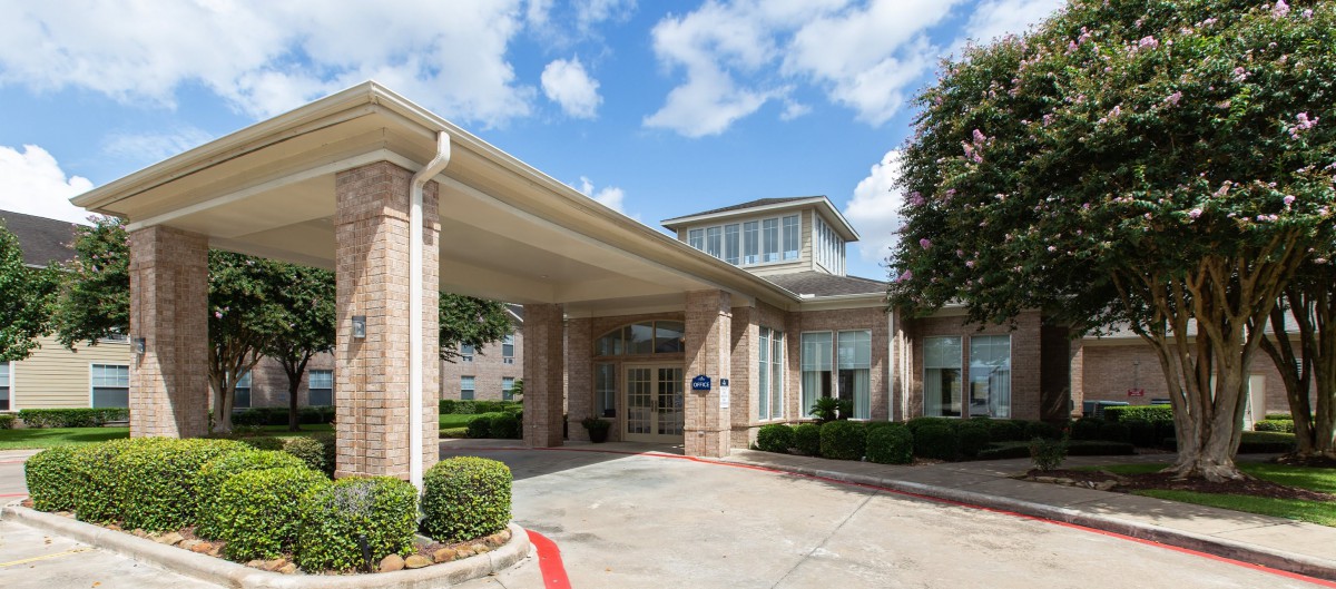 The entrance of a hotel with a covered driveway and well-maintained landscaping.