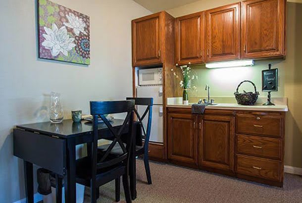 A cozy kitchen and dining area featuring wooden cabinets, a small dining table with chairs, and decorative elements.