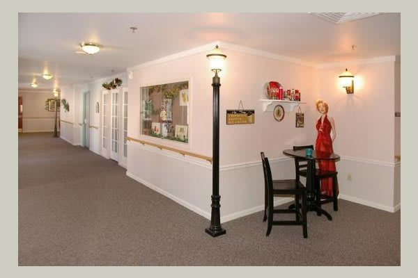 A warmly decorated hallway featuring artwork, furniture, and a floor lamp.