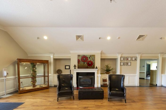 A spacious living room featuring a fireplace, two black chairs, and elegant decor.