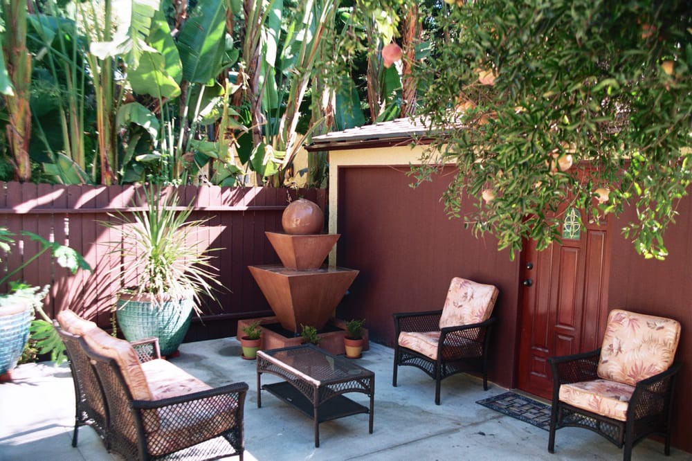 A cozy patio area with outdoor seating and a fountain surrounded by lush greenery.
