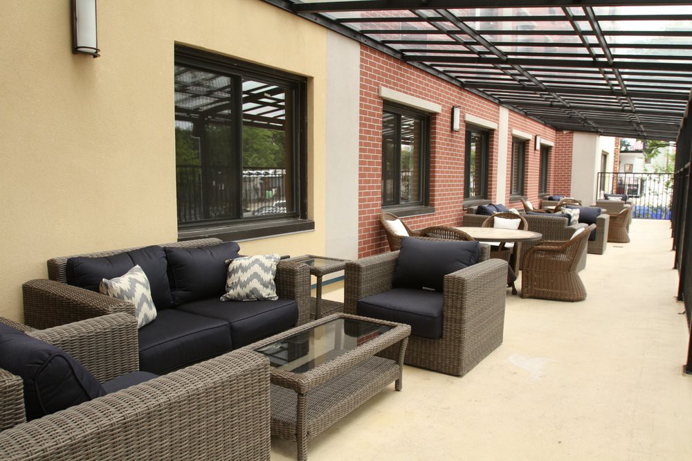 A modern outdoor patio with wicker furniture and a glass table on a terrace.
