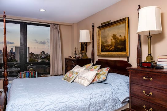 A cozy bedroom with elegant decor, featuring a large bed, decorative pillows, and a scenic window view.