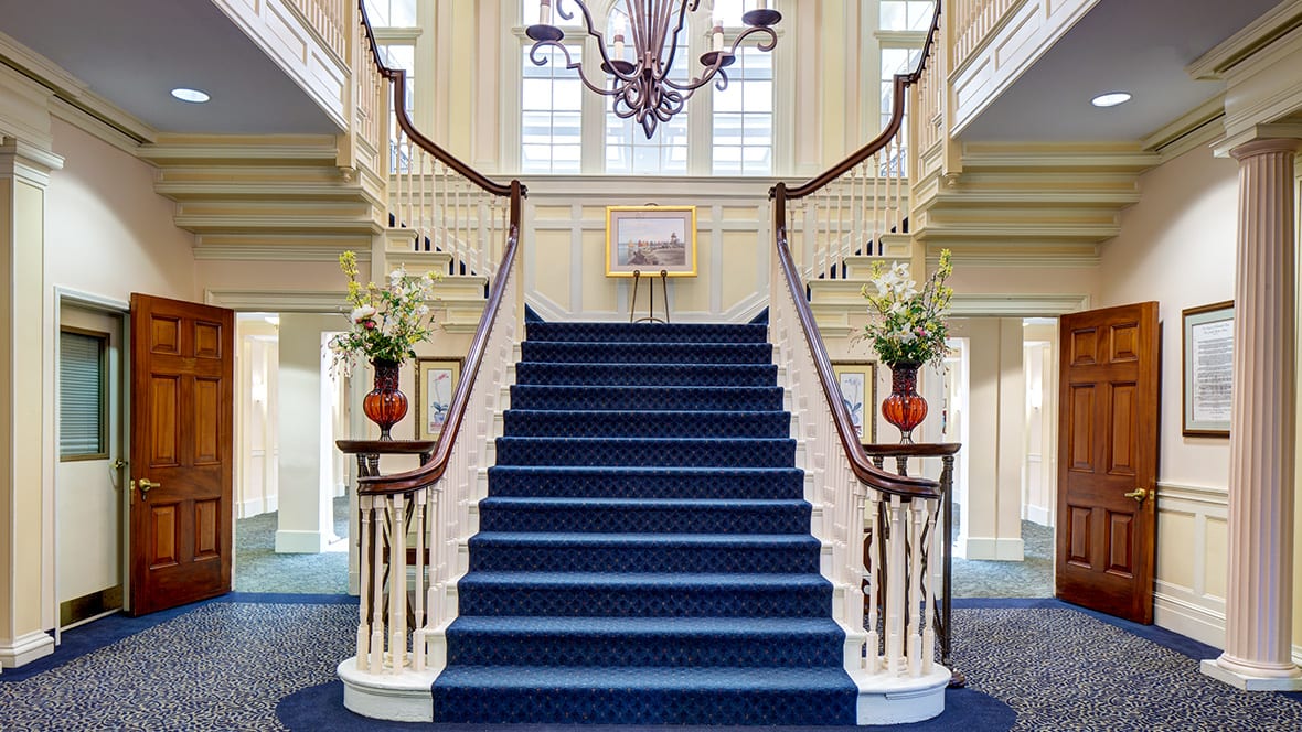 A grand, symmetrical staircase with a blue carpet and elegant decorations.