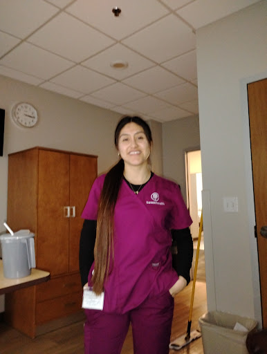 A healthcare professional in scrubs stands confidently in a hospital setting.