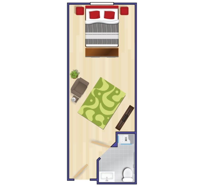 A floor plan of a small bedroom with a bed, rug, desk, and an attached bathroom.