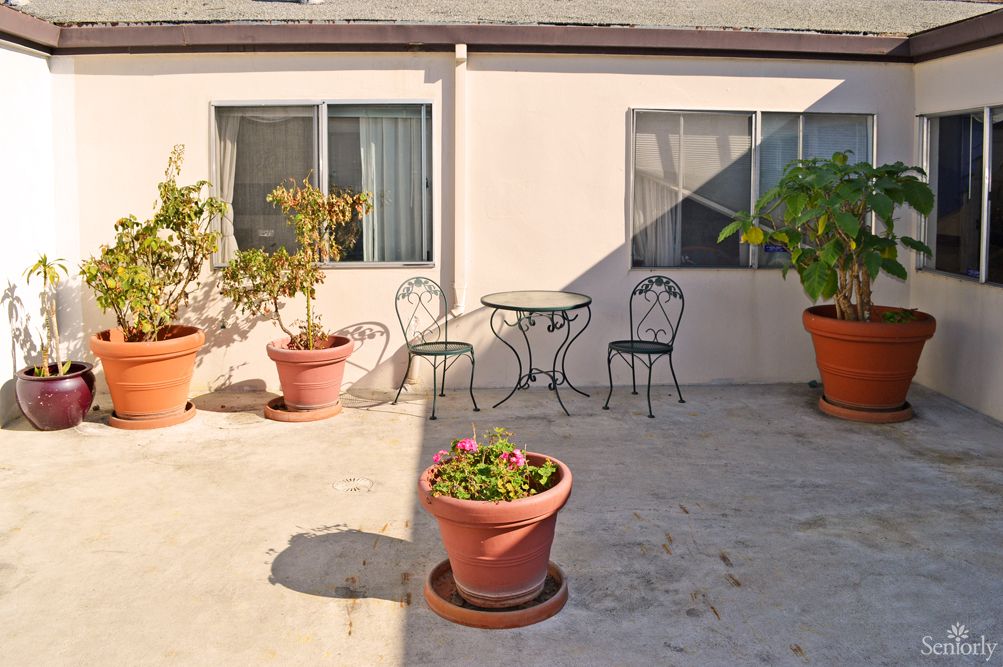 A sunny patio with potted plants and wrought iron furniture.