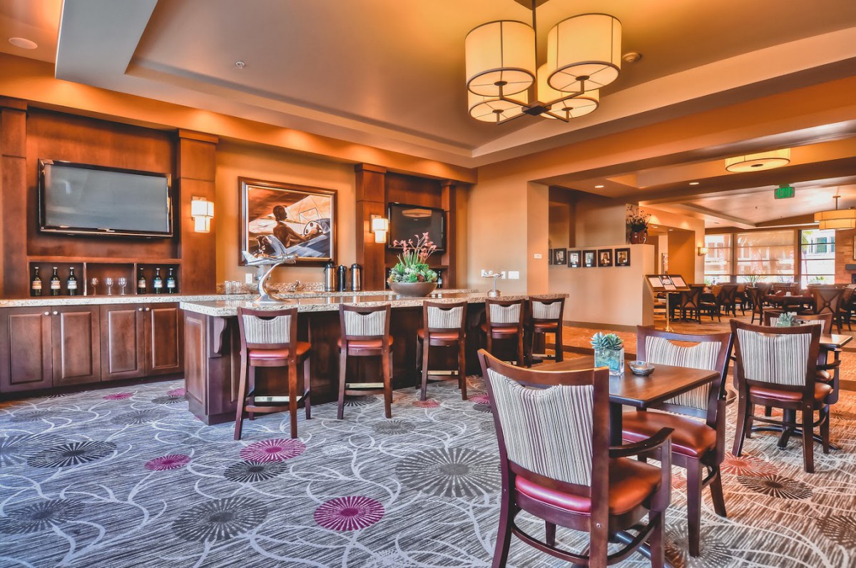 A cozy restaurant interior with a bar and seating area, featuring elegant decor and warm lighting.