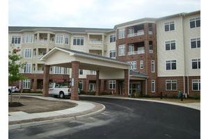 A multi-story residential building with a covered entrance and a car parked in the driveway.