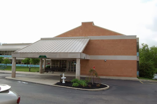 A modern brick building featuring a covered entrance and landscaped surroundings.