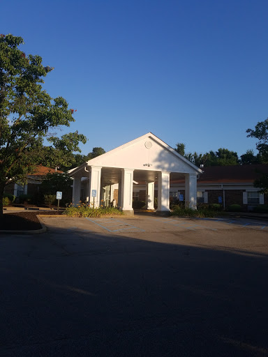 A peaceful hotel entrance bathed in morning sunlight, surrounded by greenery.