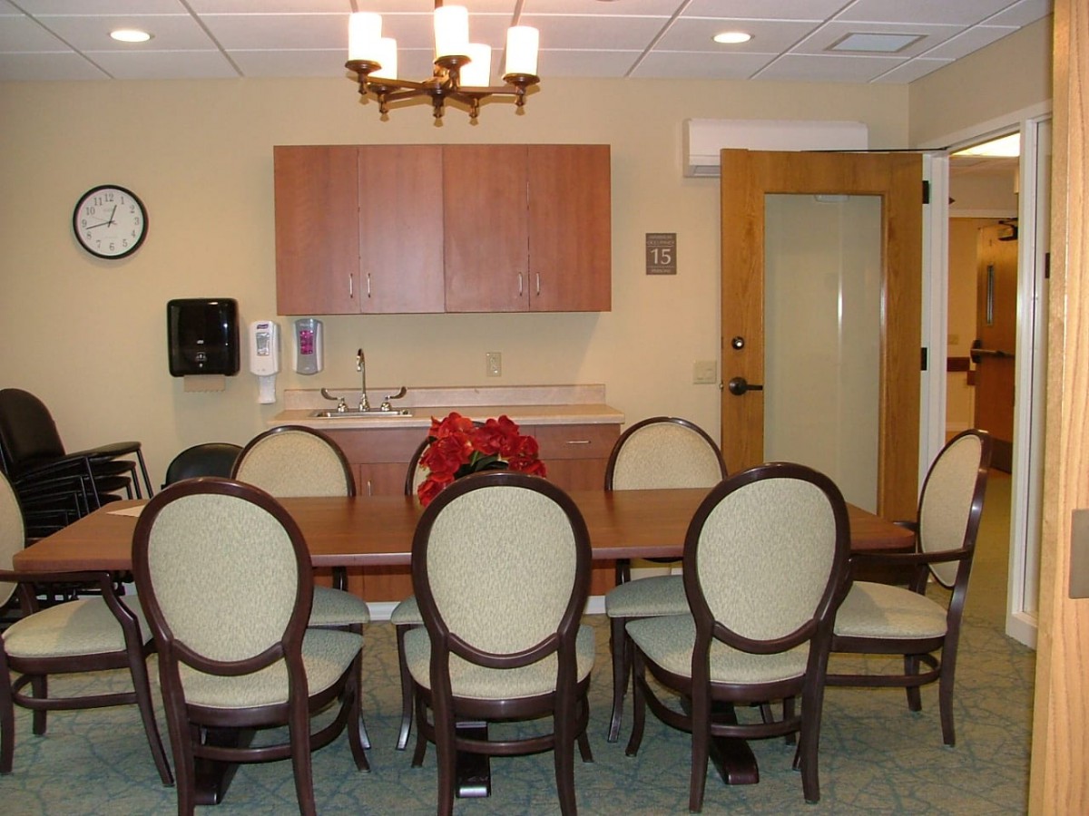 A conference room with a large meeting table and chairs, featuring a chandelier and cabinets.