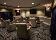 A modern lounge area with comfortable seating and a large television, featuring ambient lighting and contemporary decor.