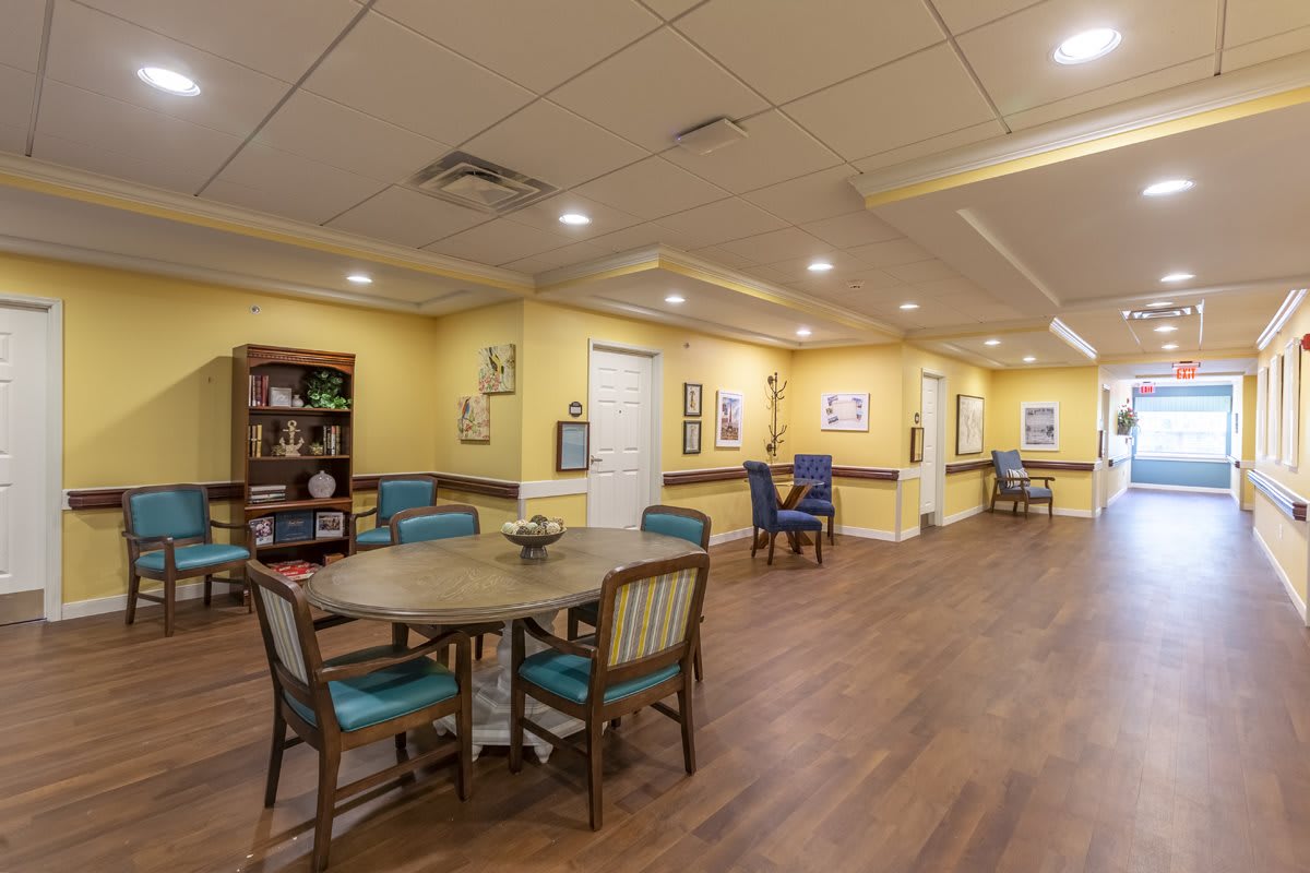 A cozy common room with tables and chairs, warm lighting, and decorative elements.