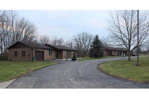 A suburban house with a winding driveway and bare trees in winter.