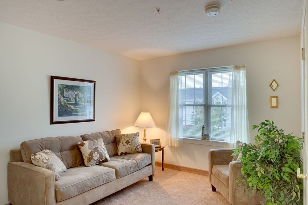 A cozy living room with a sofa, armchair, and a lamp by the window.