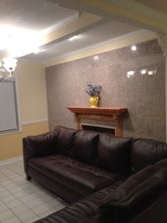 A cozy living room with a dark sofa and a decorated fireplace.