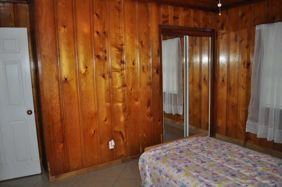 A cozy bedroom with wood-paneled walls and a mirrored closet door.