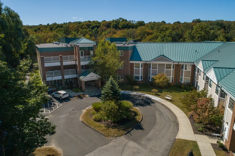 Aerial view of a building with a circular driveway surrounded by trees.