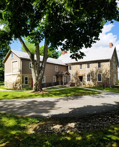 A charming stone house surrounded by lush greenery and a clear blue sky.