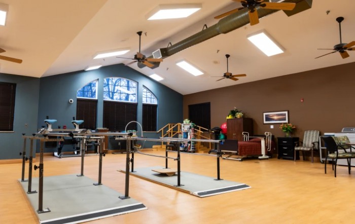 A spacious rehabilitation room equipped with parallel bars and other physical therapy equipment.