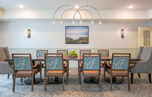 A modern dining space featuring a large table with stylish chairs, complemented by elegant lighting and a serene artwork on the wall.