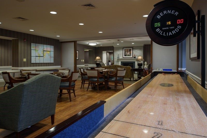 A cozy game room featuring a shuffleboard table and comfortable seating.