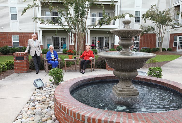 Seniors enjoying a peaceful afternoon in a courtyard garden with a fountain.