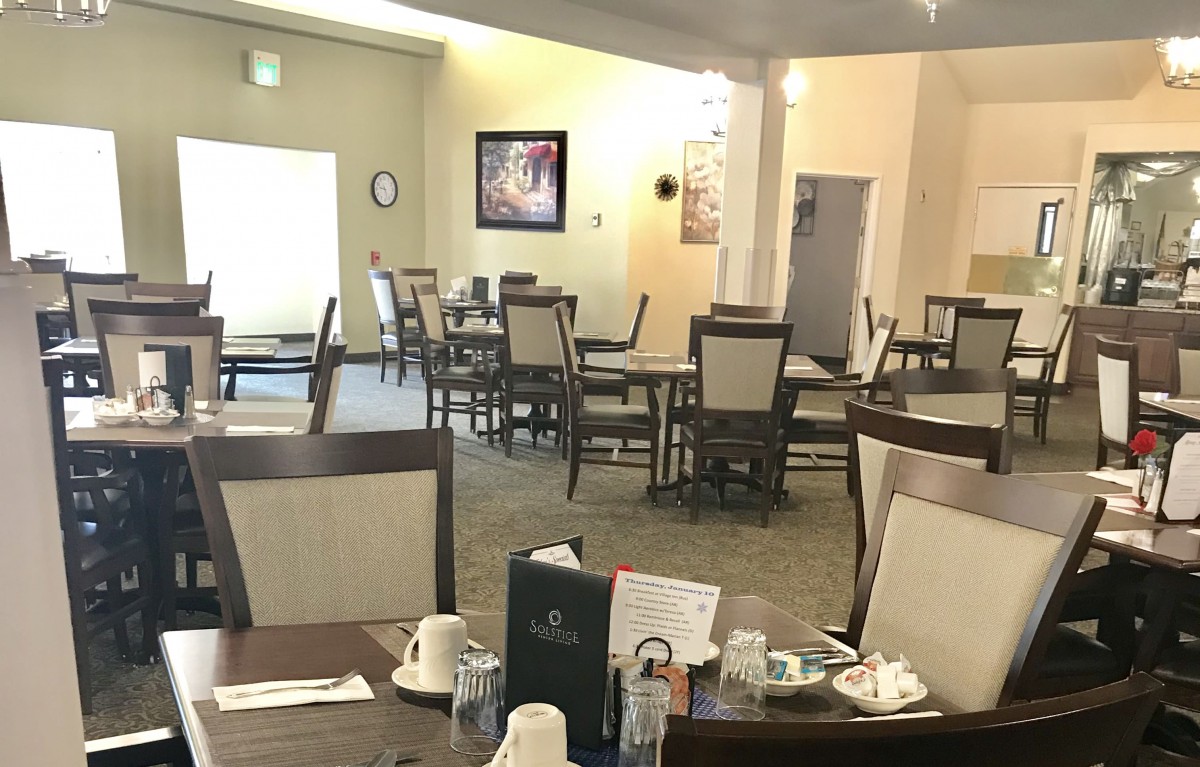 An empty dining area in a restaurant with neatly arranged tables and chairs.