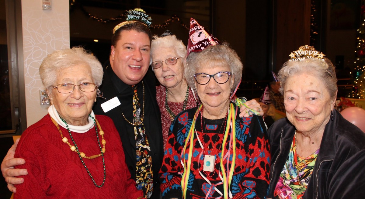 A joyful group of people wearing party hats, celebrating together with smiles and festive decorations.