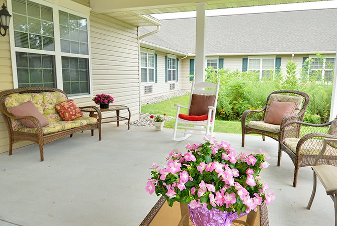 A cozy porch with comfortable seating and vibrant pink flowers, ideal for relaxation.