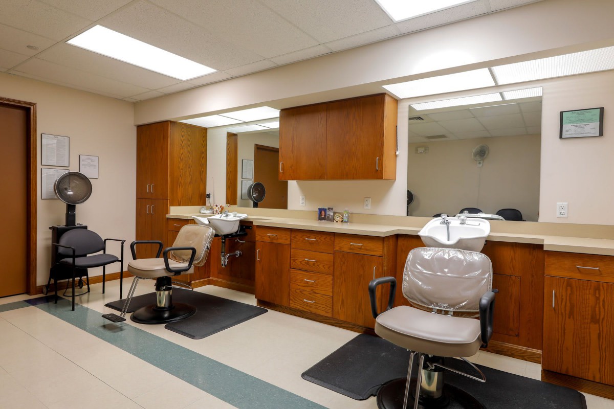 Interior view of a barbershop with chairs and mirrors along the counter.