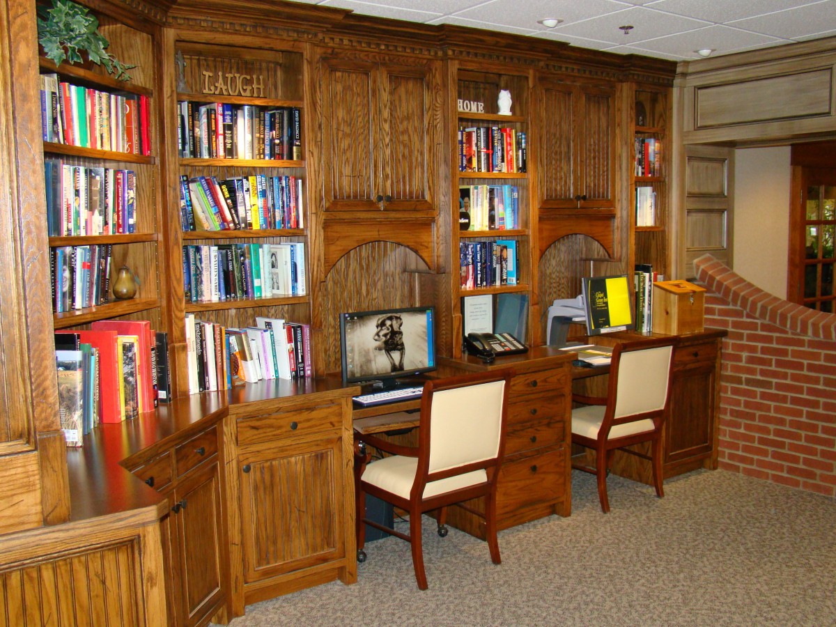 A cozy library with wooden bookshelves, computers, and seating for study.