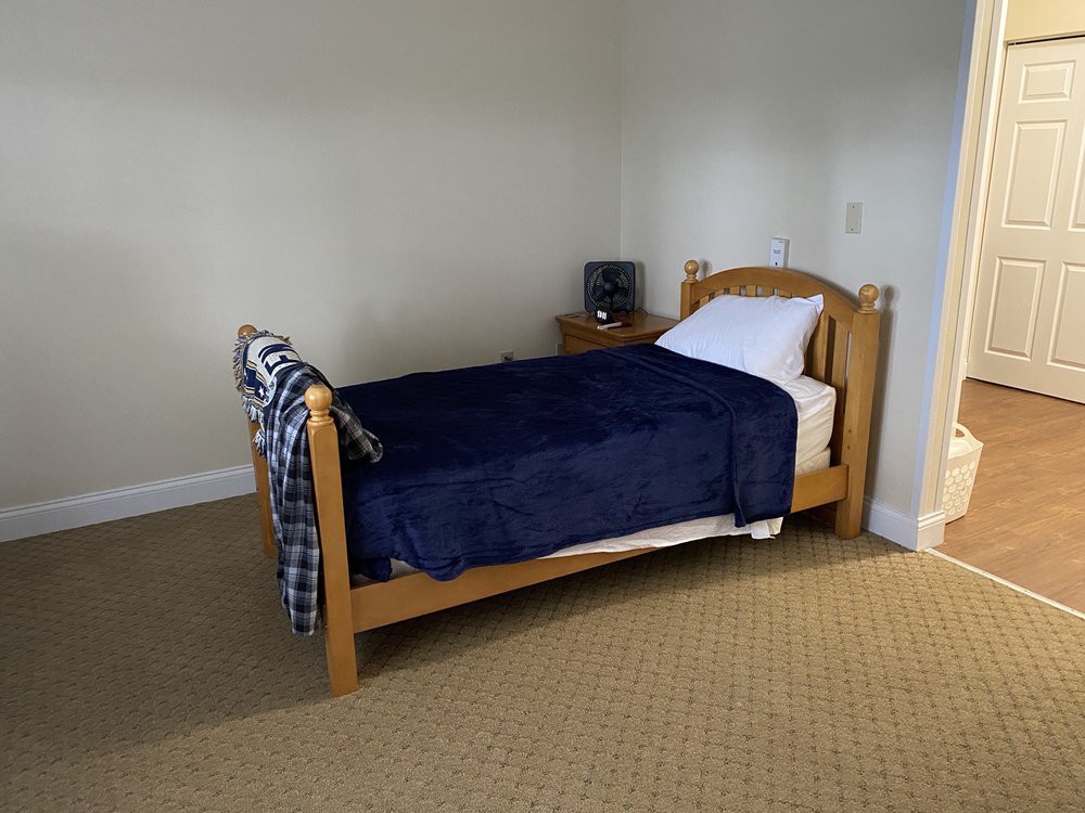 A simple bedroom with a single wooden bed and blue blanket.