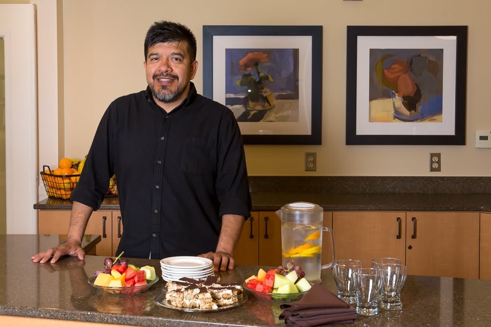 A man standing behind a counter with an assortment of food and drinks.