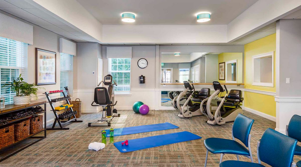 A well-equipped gym with yoga mats, exercise machines, and free weights.