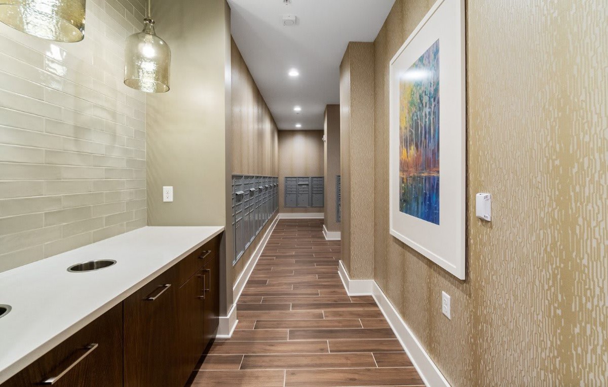 A modern hallway with elegant lighting, wood flooring, and framed artwork on the wall.