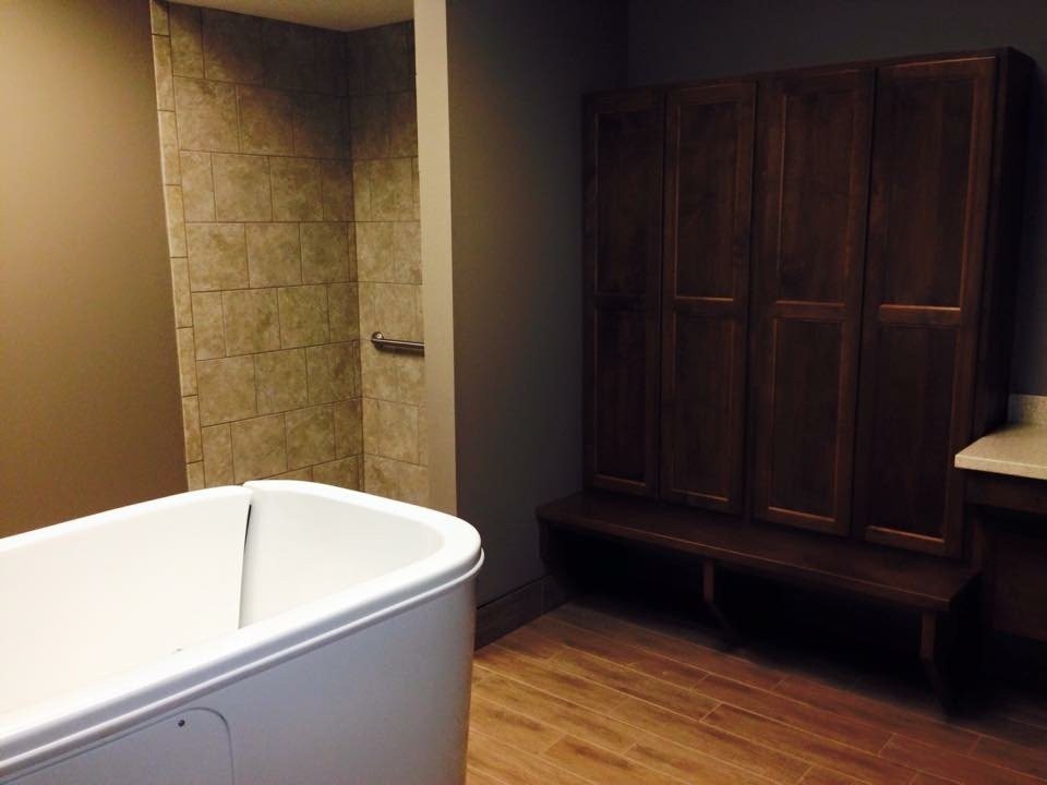 A modern bathroom featuring a freestanding tub, tiled shower, and wooden locker with bench seating.
