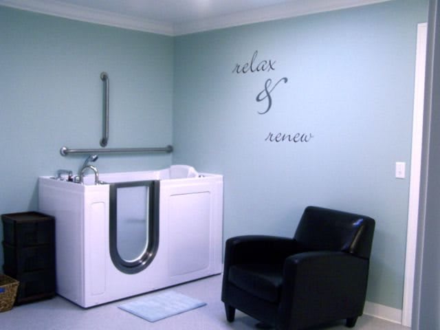 A serene bathroom featuring a walk-in tub and a comfortable armchair, creating a spa-like atmosphere.
