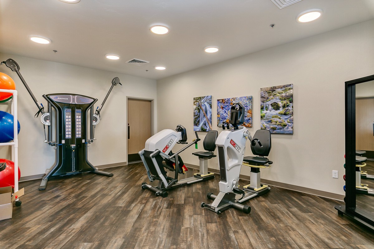 A modern gym with exercise machines and wooden flooring.