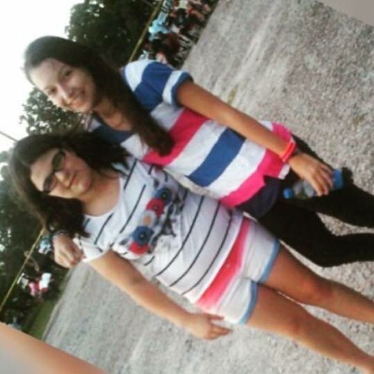 Two friends smiling outdoors in casual striped shirts.