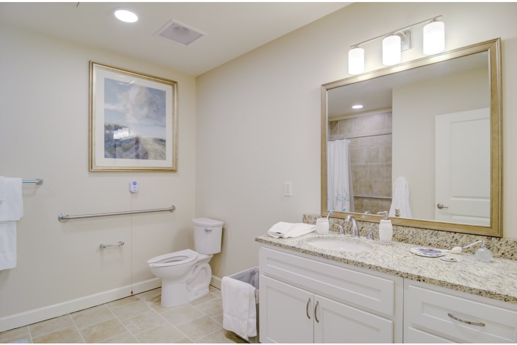 A modern bathroom with a sink, mirror, toilet, and decorative artwork.