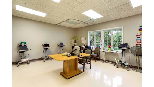 A well-lit therapy room designed for rehabilitation sessions, featuring a central table and therapy equipment.