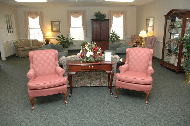 A cozy living room with two pink armchairs, a wooden coffee table, and various plants for decoration.