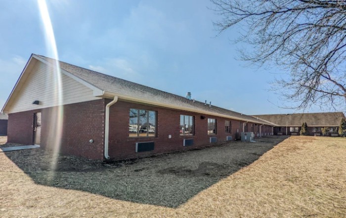 A one-story brick building with several windows and a sloped roof.