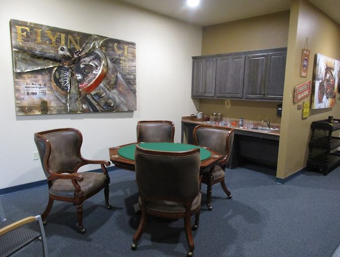 A small meeting room with a round table, four chairs, and artwork on the wall.
