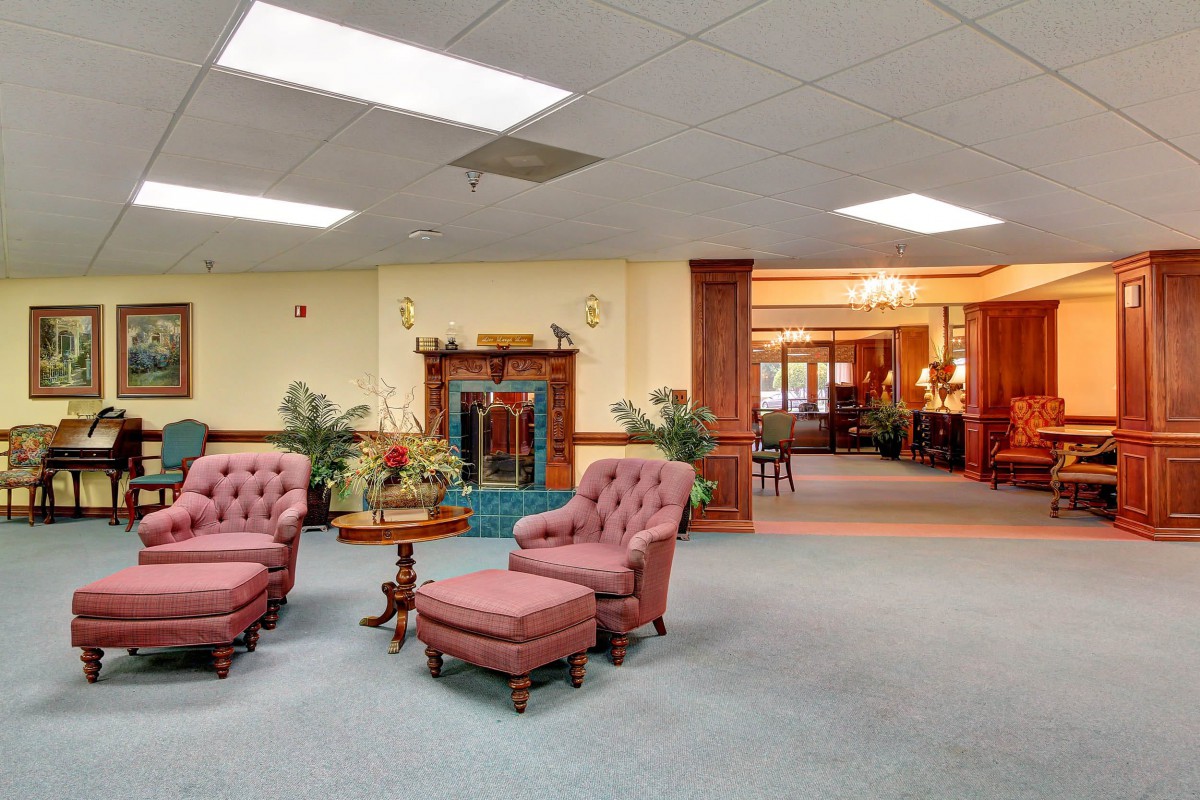 A traditional lobby interior with pink upholstered chairs and a fireplace.