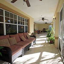 A sunny porch with comfortable seating, ceiling fans, and plants.