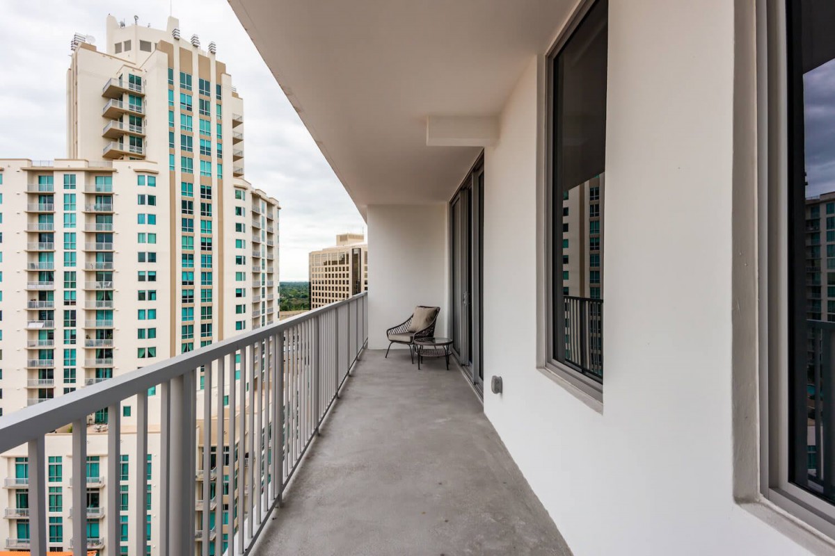 A modern apartment balcony with city views and high-rise buildings in the background.
